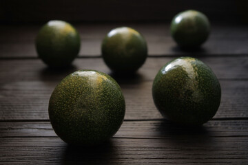 Concept, avocado fruit on a black wooden background. Green colored avocado fruit is a rich source of fat-soluble vitamins, minerals and fiber. Creative presentation of avocado fruit in the hands of a 
