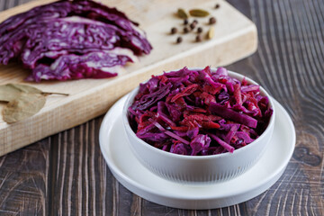 Homemade pickled red cabbage in white ceramic bowl. Close up