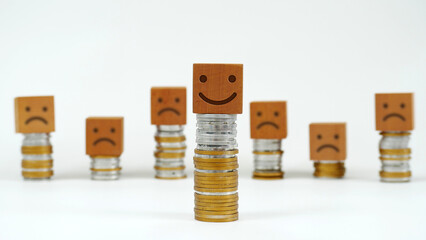 closeup of a smiley face on wood above a pile of coins with a blurred background of coins and sad...