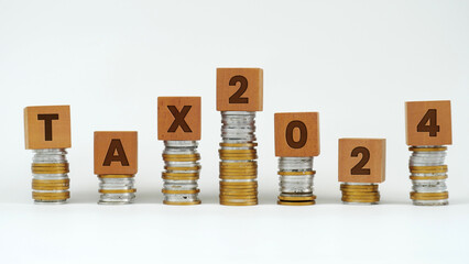 Word Tax 2024 on wooden cubes above a pile of coin charts. Calculation tax return. Accounting