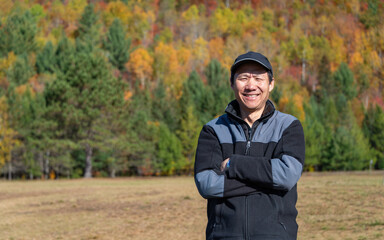 Tourist posing for photos in a park with autumn colours in the background. Mont Tremblant. Quebec. Canada. - 778775217