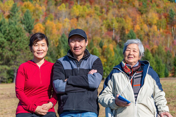 Senior woman and family posing for photos in a park with autumn colours in the background. Mont Tremblant. Quebec. Canada. - 778775255