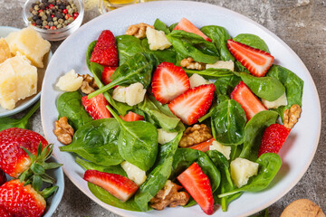 Healthy summer salad with spinach, strawberries, parmesan cheese, walnuts and olive oil in a plate. Delicious vegetarian food for lunch. Tasty appetizer - 778781836