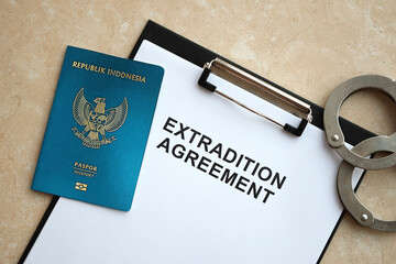 Passport of Indonesia and Extradition Agreement with handcuffs on table close up