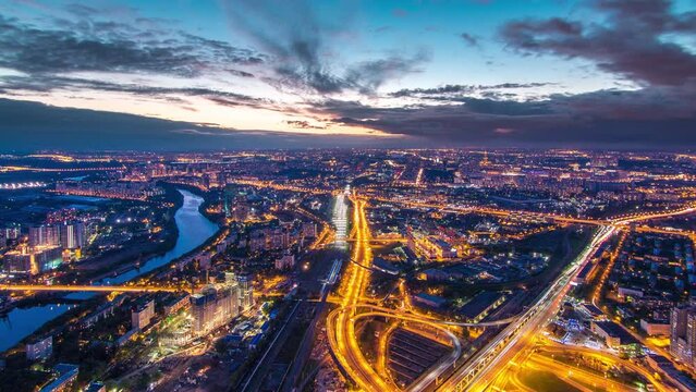 Aerial top view of Moscow city day to night transition timelapse after sunset. From the observation platform of the business center of Moscow City. Moscow river and traffic on roads at summer evening