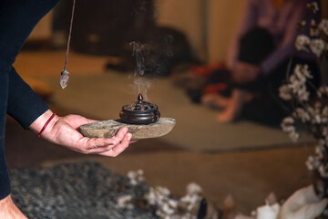 a person holding an incense burner standing on a stone purifying the energy of the place