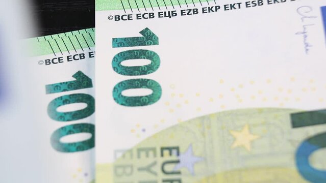 A man counts out 100 euro banknotes and places them one by one on a black office desk