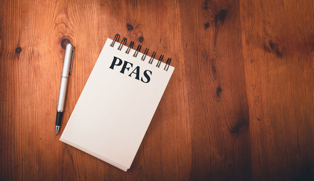 note pad on wooden table  with pfas, per- and polyfluoroalkyl substances , concept of eternal or forever chemicals and pollution ,copy space .