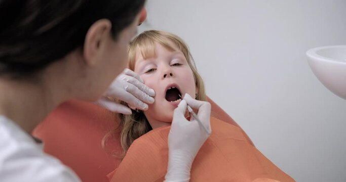 A little girl is happily getting her teeth examined by a dentist