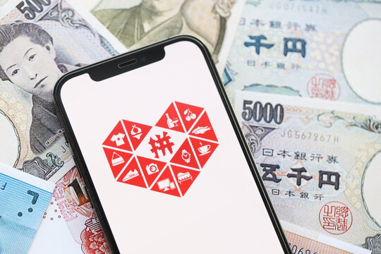 KYIV, UKRAINE - APRIL 1, 2024 Pinduoduo icon on smartphone screen on many asian money bills. iPhone display with app logo with japanese yen and chinese yuan banknotes
