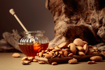 Almond nuts in a wooden dish and honey in a glass jar.