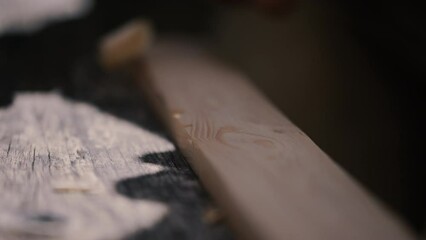 Carpentry, wood shaving being removed by craftsman preparing his work piece for hand planing. Wooden plank into cross