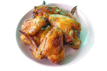 Thai food - Grilled Chicken Wings on white plate and white background. Chicken wings marinated in sweet sauce Thai people like to eat it with papaya salad and fresh vegetables.