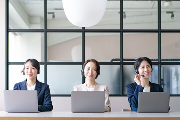 ヘッドセットをつけてパソコン作業をする女性