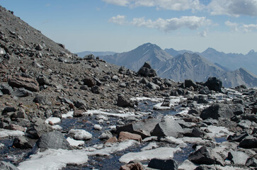 the melted snow flows down in a stream among the rocks in the mountains