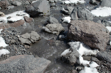 the melted snow flows down in a stream among the rocks in the mountains