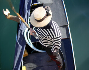 Gondolier in Venice rows a gondola on the Grand Canal - obrazy, fototapety, plakaty