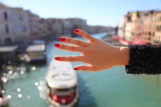 Hand of girl with slender fingers and red-polished nails and Venice Grand Canal