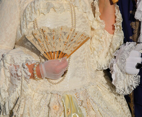gloved hand holding fan of noble lady in antique and luxurious garments