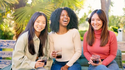 Multiethnic friends smiling at camera while drinking in the garden