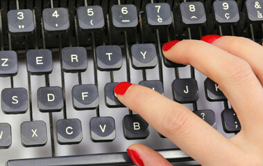 Secretary s red-polished fingernails typing on the keys of an old typewriter in an office