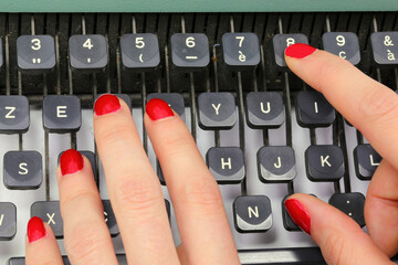 polished nails of Female secretary typing on the keys of an old typewriter in an office