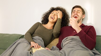 Couple laughing while watching fun film at home
