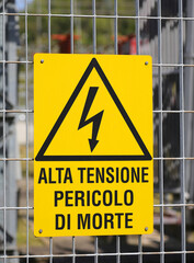 Sign in the fence of the power station with the large text in Italian meaning High Voltage Danger of Death