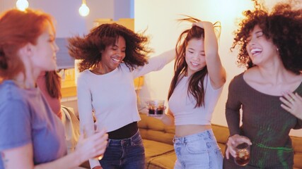 Multiethnic women dancing happily in a night party at home