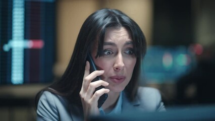 Portrait of beautiful Caucasian worker talking with her client or colleague on phone. Young woman having stressed conversation on smartphone while looking at computer screen. Disappointment at work.