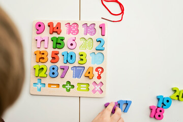 kid learning numbers through game. Sensory activity with wooden numbers and shoe laces. Educations at home, pre-school education, Montessori methodology. sequence of numbers, arithmetic problems. - obrazy, fototapety, plakaty