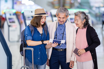 Group of Asian family tourist  passengers with senior parent is looking at the boarding pass after self check kiosk in at airport terminal for international travel flight and vacation