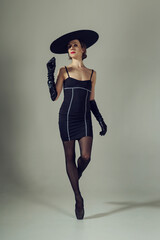 ballerina in the style of fashion total black in a dress, hat and gloves poses ballet elements