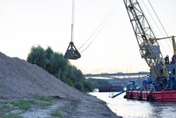 Barge loading sand by the crane. River in mountain region in Vietnam