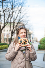 Beautiful woman holds bagel outdoor on the street in Belgrade, Serbia