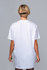 Woman dressed in a white oversized t-shirt with blank space, ideal for a mockup, set against gray background