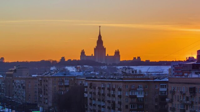 Timelapse of a winter sunset over Moscow State University, captured from a top view along Komsomolskiy Avenue, with rooftops in the foreground