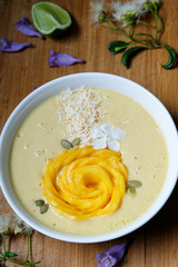 Mango, Pineapple, Passion fruit, Banana and oat coconut milk smoothie bowl topped with fresh mango, toasted shredded coconut and pumpkin seeds 