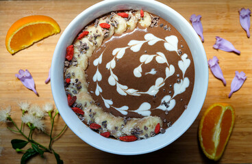 Chocolate smoothie bowl, made from raw cacao and banana and oat milk topped with cacao nibs, toasted shredded coconut, goji berry and match granola, chia and flax seeds 