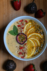 Mango, Pineapple, Passion fruit, Banana and oat coconut milk smoothie bowl topped with fresh orange, mango, kiwi, toasted shredded coconut and pumpkin seeds	