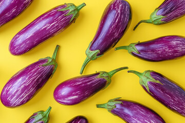 Fresh purple eggplants on vibrant yellow background, top view, flat lay