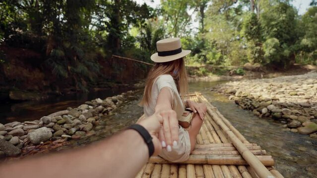 Female tourist floats on bamboo raft. Woman tourist enjoying the bamboo rafting on the river with man beautiful nature landscape on smartphone. Vacation, adventure, travel, follow me concept.