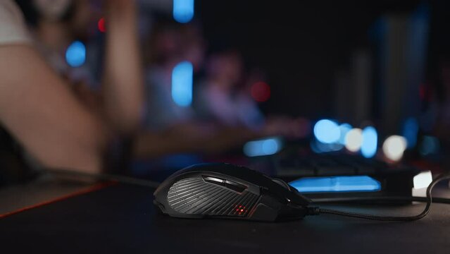 Close up professional computer PC gaming mouse with RGB lighting animation idle at computer club during E-sport tournament, cyber team. Five gamers play video game. Tactics strategy. Modern equipment