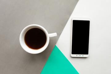 Fototapeta na wymiar Coffee cup and black mockup phone on color background. Flat lay photo, minimal concept