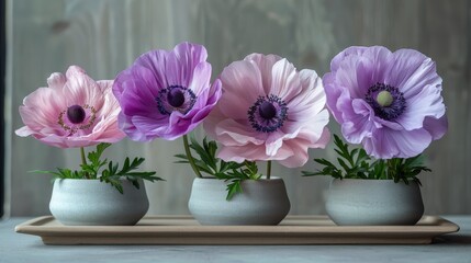   Three vases with pink and purple flowers on a wooden tray against a wooden wall