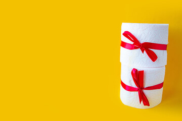 toilet paper rolls wrapped in gift bow. Bright yellow background. Copy space for the text. Covid19...