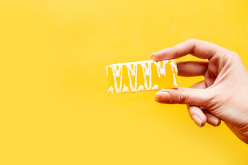 Woman 's hand holds a cake over yellow background, minimal concept