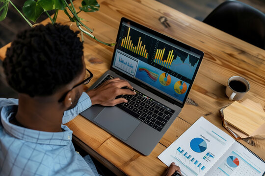 African American man financial analyst working on a laptop screen with business data analysis.