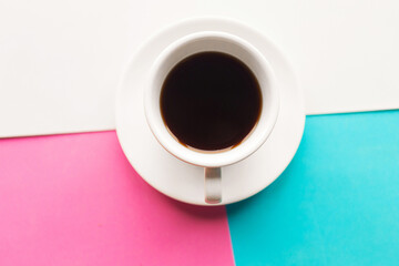 Coffee cup on geometric pink, blue and white background. Top view, minimal concept.