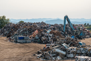 Clow crane picking up scrap metal at recycling center for metal, aluminum, brass, copper, stainless steel in junk yard. Recycling industry. Environment and zero waste concept - obrazy, fototapety, plakaty